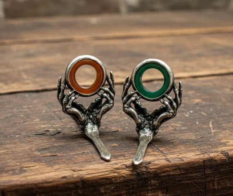 Pair of guides shaped like hands holding rings on a wooden surface with stone wall background