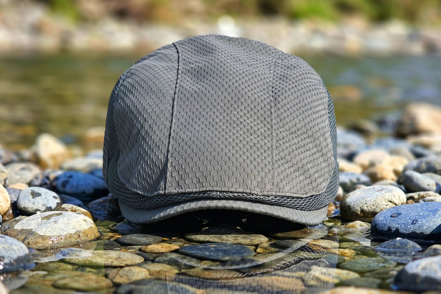 Gray cap on pebbles with water and greenery in the background