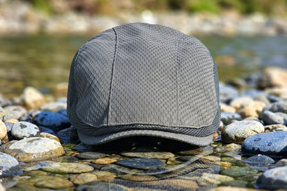Gray cap on pebbles with water and greenery in the background