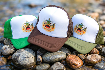 Three trucker hats with fish designs on a rocky surface