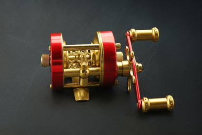 Gold and red fishing reel on a black background
