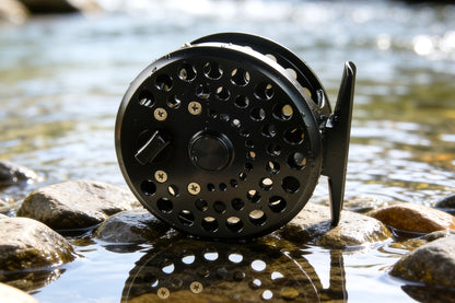 Fly fishing reel on a rock by a stream